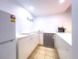 a small kitchen with white cabinets and a microwave at Tropical Mango House Stay in Airlie Beach