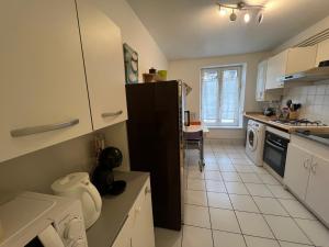 una cucina con frigorifero nero e pavimento piastrellato bianco di Le Central Victoria VII - Central district - Stanislas - Train station a Nancy