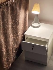 una lampada accanto a un comodino bianco con un cassetto di The Horse Monument Hostel a Belgrado Altre 14 foto