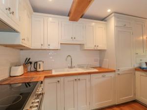 a kitchen with white cabinets and a sink at Greenham Rise in Chiselborough