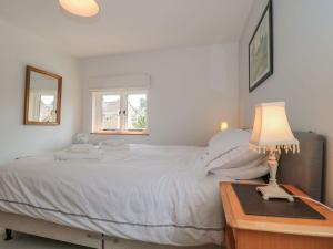 a bedroom with a white bed and a table with a lamp at Greenham Rise in Chiselborough