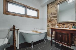 a bathroom with a tub and a sink at Thedell Cottage - A Boutique Heritage Escape in Auburn +17 photos