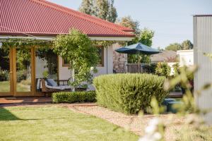 a house with an umbrella in a yard at Thedell Cottage - A Boutique Heritage Escape in Auburn