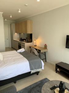 a bedroom with a bed and a desk and a kitchen at Ellipse Luxurious Tamarind Red Studio Experience in Midrand +39 photos