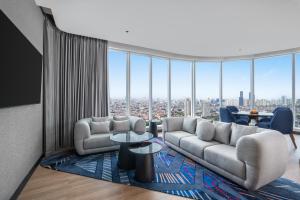 a living room with couches and a view of a city at Novotel Jakarta Pulo Mas in Jakarta