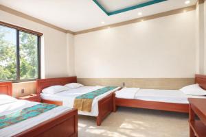 two beds in a room with two windows at Khách Sạn - Cà Phê Dinh Cô in Long Hai