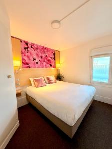 een slaapkamer met een groot bed met een bloemschilderij aan de muur bij Fasthotel Orleans Zénith in Orléans