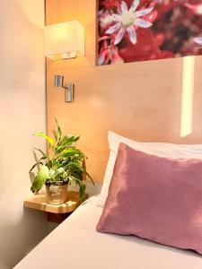 een slaapkamer met een plant op een bed bij Fasthotel Orleans Zénith in Orléans