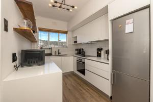 a kitchen with white cabinets and a refrigerator at Table Mountain Views - Stylish Gardens Apartment in Cape Town