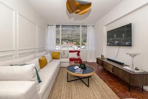 a living room with a white couch and a table at Table Mountain Views - Stylish Gardens Apartment in Cape Town