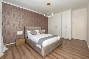 a bedroom with a large bed and a pink wall at Table Mountain Views - Stylish Gardens Apartment in Cape Town