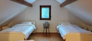 two beds in a attic room with a window at CaSa ViTo Kumrovec in Brezje