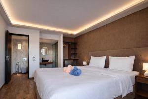 een groot wit bed met een blauw knuffeldier erop bij Villa Park Luxury Rooms in Paralion astros