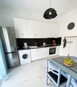 a kitchen with white cabinets and a stainless steel refrigerator at Sadin apartment in Neos Marmaras
