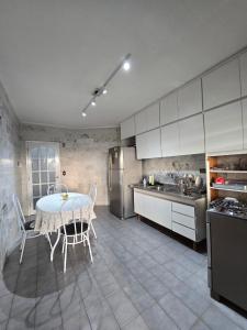 a kitchen with a table with chairs and a refrigerator at Refúgio da Zena in Mairiporã