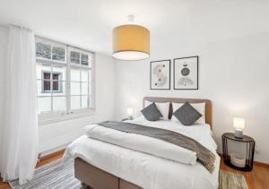 a white bedroom with a large bed and a window at The R Apartment Hemmental in Schaffhausen
