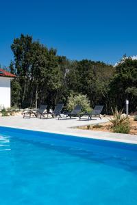 a group of chairs sitting next to a swimming pool at Villa Cyprian by Villas Guide in Kampor