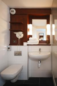 een badkamer met een wastafel, een toilet en een spiegel bij Brit Hotel Confort Orly Morangis in Morangis