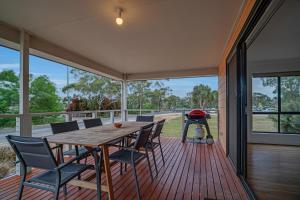a screened porch with a wooden table and chairs and a grill at Long Island Retreat - Rosella in Murray Bridge