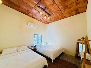 two beds in a room with wooden ceilings at MIA Villa in Tiến Thành