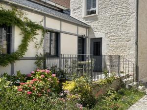 a white brick house with a balcony with flowers at Le Clos de l'Armançon - Maisons de charme au bord de la rivière - Classé 4 étoiles in Tonnerre +69 photos