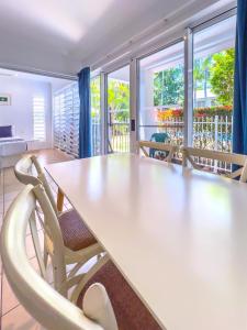 a dining room with a white table and chairs at Coastal at Mango House in Airlie Beach