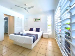 a white bedroom with a bed and a staircase at Coastal at Mango House in Airlie Beach