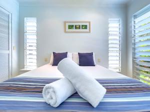a bedroom with a bed with towels on it at Coastal at Mango House in Airlie Beach