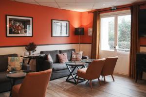 een woonkamer met een bank en een tafel bij Brit Hotel Confort Orly Morangis in Morangis