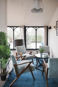 een woonkamer met stoelen en een tafel en ramen bij Brit Hotel Confort Orly Morangis in Morangis