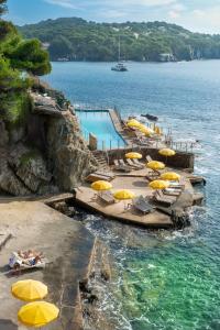 een zwembad met gele parasols en stoelen in het water bij Hôtel Le Provençal - Rénové en 2025 - Bord de Mer in Hyères