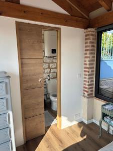 a bathroom with a wooden door and a toilet at Le clos des Oiseaux in Itzac
