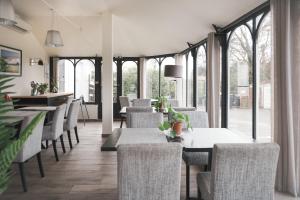 een restaurant met tafels, stoelen en ramen bij Brit Hotel Confort Orly Morangis in Morangis +26 foto's