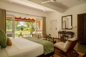 a bedroom with a large bed and a large window at Mimosa Hill in Hiriketiya