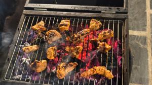 a grill with chicken and other food on it at Eva Cabins in Dalhousie