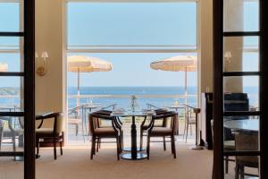 een eetkamer met een tafel en stoelen en uitzicht op de oceaan bij Hôtel Le Provençal - Rénové en 2025 - Bord de Mer in Hyères