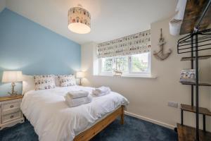 a bedroom with a bed with white sheets and a window at 1 Lavender Cottages, Knodishall in Saxmundham