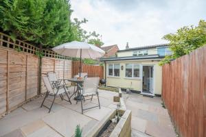 a patio with a table and chairs and an umbrella at 1 Lavender Cottages, Knodishall in Saxmundham