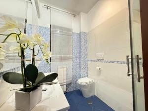 a bathroom with a toilet and a vase of flowers at Casa Letizia in Ladispoli +15 photos