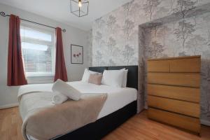 a bedroom with a large bed and a dresser at Stylish 3BR House - Sleeps 5 - Free Parking in Ferryhill