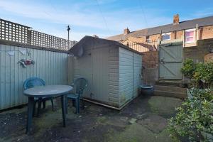a table and chairs in a backyard with a shed at Stylish 3BR House - Sleeps 5 - Free Parking in Ferryhill