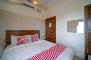 a bedroom with a bed with red and white pillows at Open Hotel by Olive - Amani Beach Stay in Māvalli