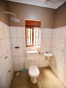 a bathroom with a toilet and a sink and a window at Nile River Inn in Buloba
