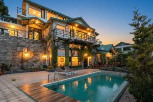 a house with a swimming pool in front of a building at Villa Mountain Crest Kasauli with Treehouse , Sundeck & Breakfast in Dagshai