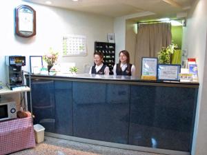 two people sitting at a counter in a store at Fuchu Urban Hotel in Fuchu