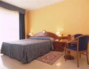 a bedroom with a bed and a desk and chairs at Hotel APAN in Reggio di Calabria