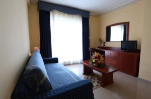 a living room with a blue couch and a television at Hotel APAN in Reggio di Calabria