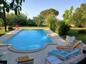 a swimming pool with lounge chairs next to a yard at Gîte de la glycine in Marmande