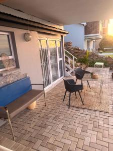 a patio with a bench and chairs on a house at Memento Vivere in Mossel Bay