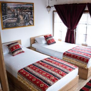 two beds in a room with a picture on the wall at Hotel Ari Old Town in Gjakove